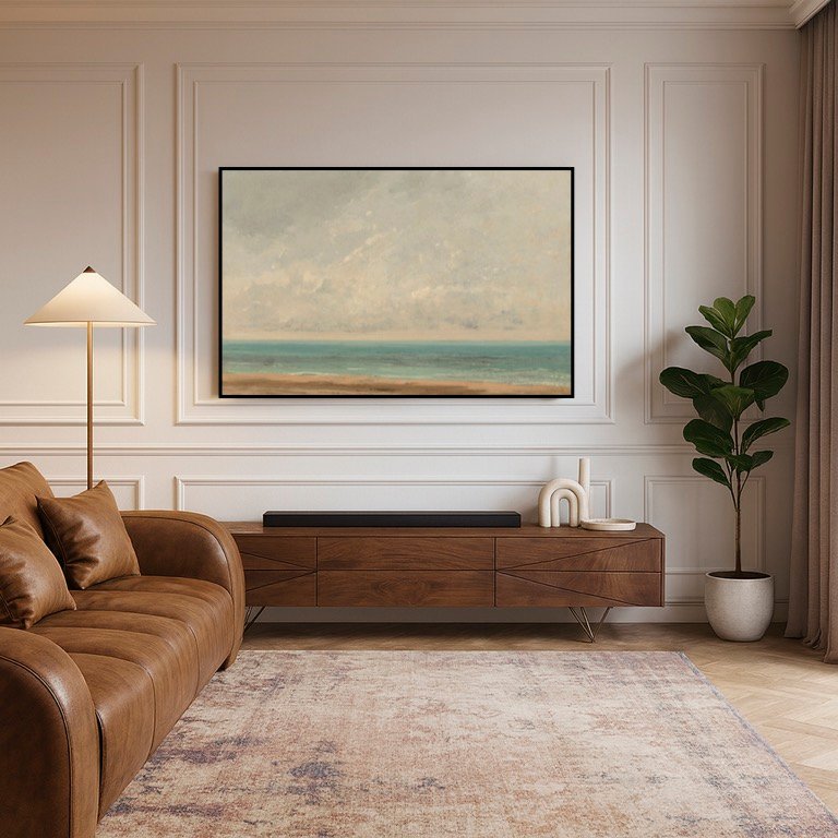 Un salon moderne avec un canapé en cuir marron, un buffet en bois, une plante en pot et un grand tableau de paysage marin au-dessus du buffet. Des tons neutres et un éclairage doux rehaussent la décoration. Contactez votre courtier en travaux Lyon pour un devis gratuit.